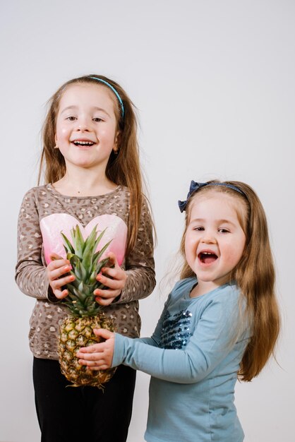 Dos niñas sosteniendo piña y sonriendo