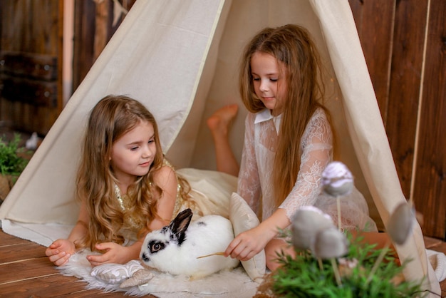 dos niñas en una tienda wigwam con un conejo, tema de Pascua