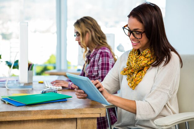 Dos niñas trabajan en la oficina en computadora y tableta