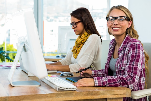 Dos niñas trabajan en la oficina en computadora y tableta