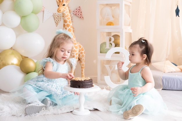 Dos niñas en vestidos azules comiendo pastel de cumpleaños de chocolate