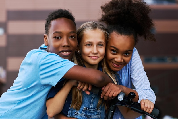 Dos niños afroamericanos abrazando a su amigo caucásico