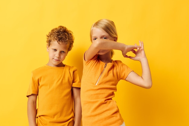 Dos niños alegres juegos de ropa informal que se divierten juntos posando fondo aislado inalterado