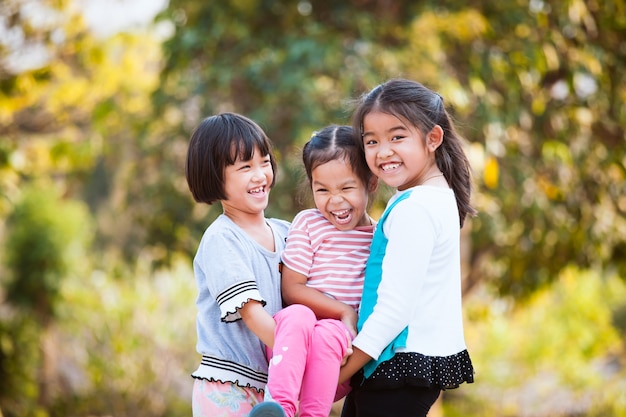 Dos niños asiáticos felices que llevan a su hermana y están jugando juntos