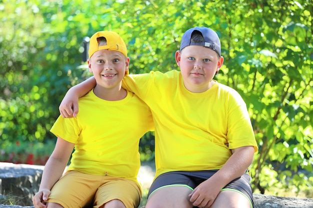 Dos niños con camisetas amarillas abrazándose sentados en el parque. Foto de alta calidad