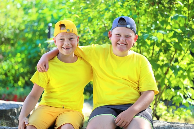 Dos niños con camisetas amarillas abrazándose sentados en el parque. Foto de alta calidad