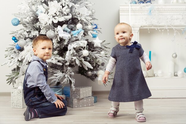 Dos niños cerca del árbol de Navidad