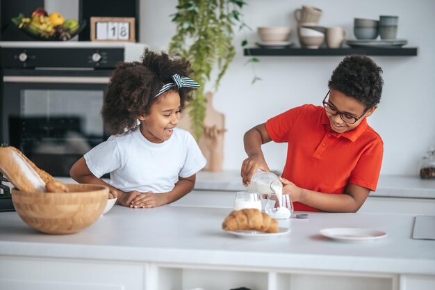 Dos niños en la cocina desayunando