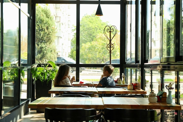 Dos niños comen helado en restaurante.