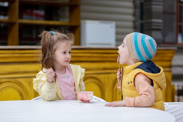 Foto dos niños comiendo helado afuera en la calle