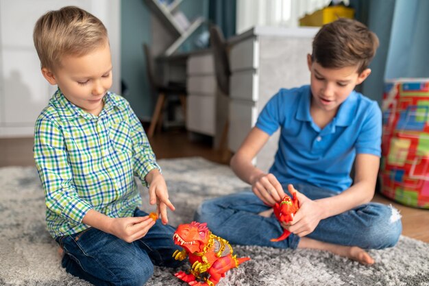 Foto dos niños concentrados en sus dinosaurios de juguete.