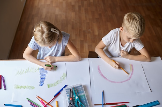 Dos niños dibujando en la mesa, vista superior