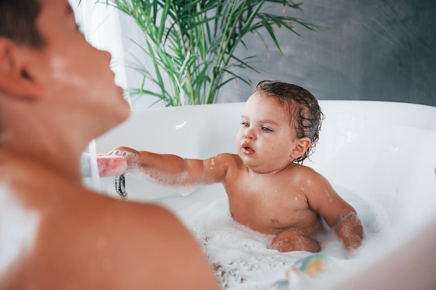 Dos niños divirtiéndose y lavándose en el baño en casa