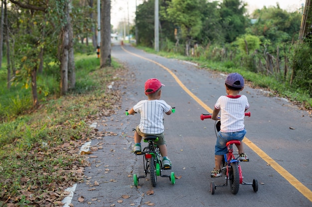 Los dos niños encantadores están montando bicicleta en la bicicleta laen.