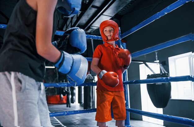 Dos niños con equipo de protección tienen sparring y peleas en el ring de boxeo.