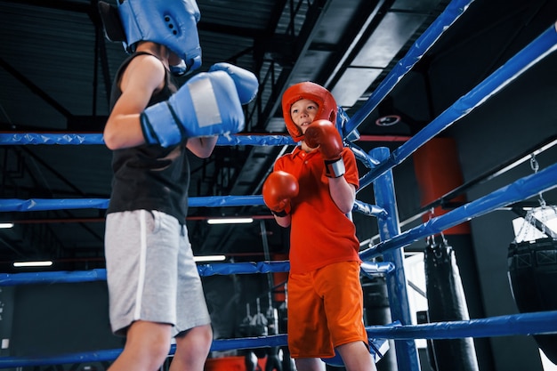 Dos niños con equipo de protección tienen sparring y peleas en el ring de boxeo.