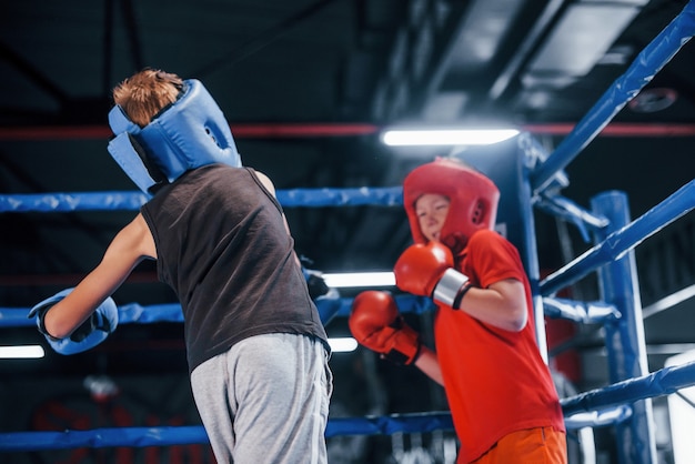 Dos niños con equipo de protección tienen sparring y peleas en el ring de boxeo.