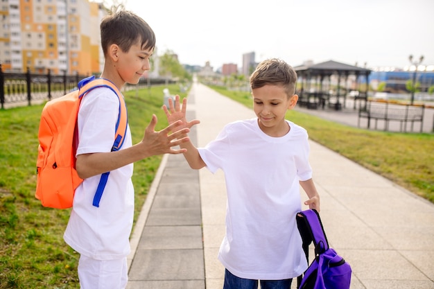 Dos niños escolares van a la escuela con mochilas brillantes.