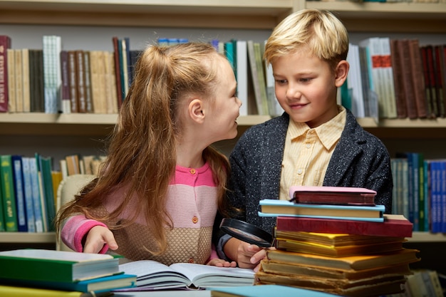 dos niños de la escuela amigables discutiendo un libro mientras leen en la biblioteca, concepto de educación. cerebro infantil, conocimiento