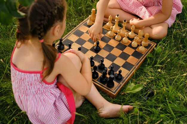 Dos niños están jugando al ajedrez en un tablero de ajedrez de madera antiguo