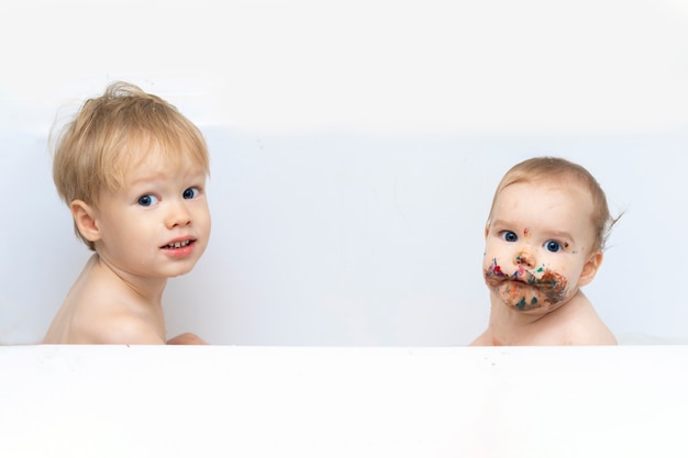 Foto dos niños están sentados en el baño, uno está limpio y el otro está sucio.