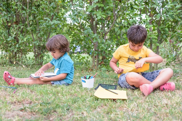 Dos niños estudiantes sentados mirando el cuaderno en el parque Concepto de primavera y vida en la calle