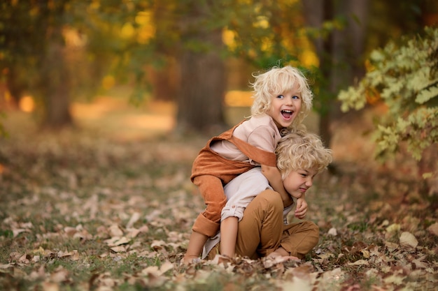 Dos niños felices están jugando en el parque a principios de otoño