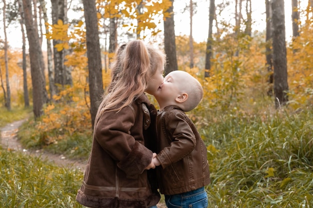 dos niños felices hermano y hermana tomados de la mano en la naturaleza en otoño