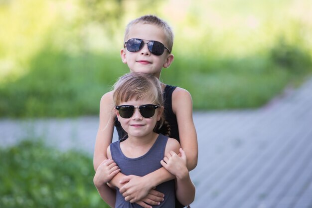 Dos niños con gafas de sol negras que se divierten al aire libre en verano.