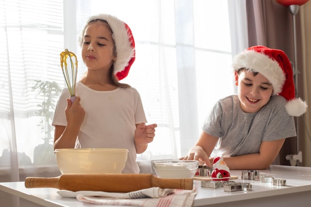 Dos niños con gorras rojas cocinan alegremente galletas en la cocina