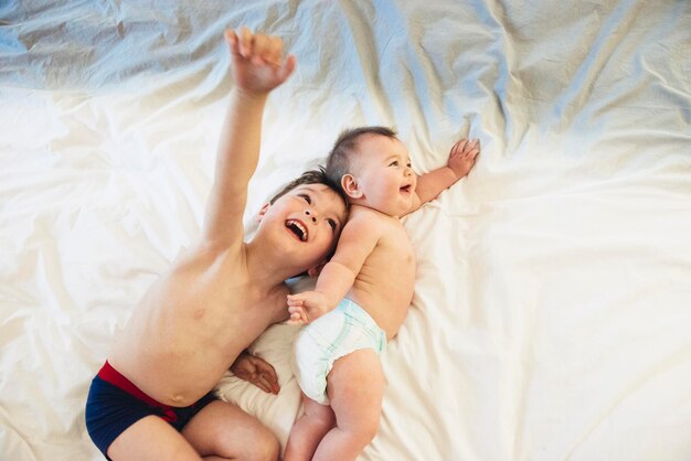 Dos niños un hermano y una hermanita acostados jugando juntos