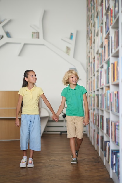 Dos niños impresionados por una variedad de libros en los estantes.