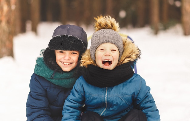 Dos niños en el invierno en la naturaleza se abrazan. Dos hermanos se divierten al aire libre