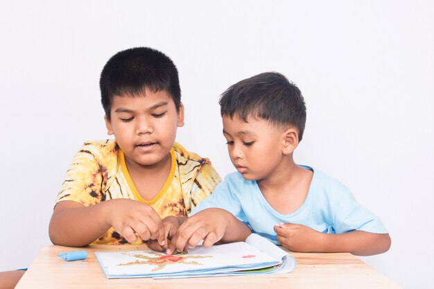 Dos niños juegan arcilla en el libro sobre fondo blanco