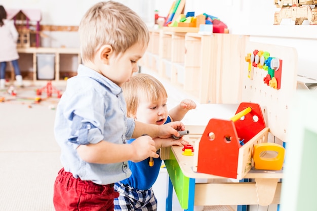 Dos niños juegan con instrumentos de madera de constructor en el jardín de infantes.