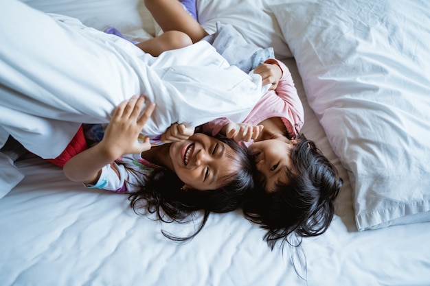 Dos niños juegan y ríen en la cama