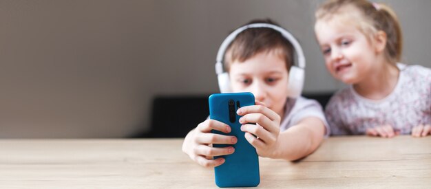 Dos niños jugando en el teléfono inteligente en auriculares