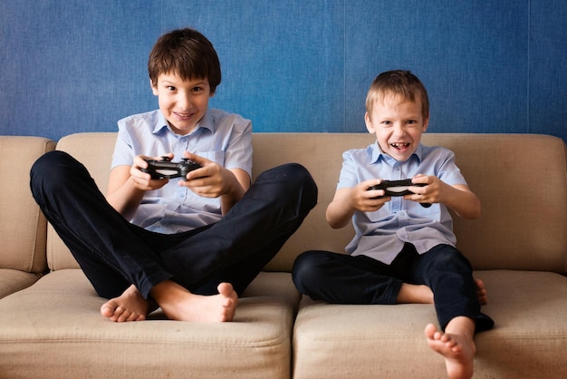 Dos niños jugando un videojuego en un sofá