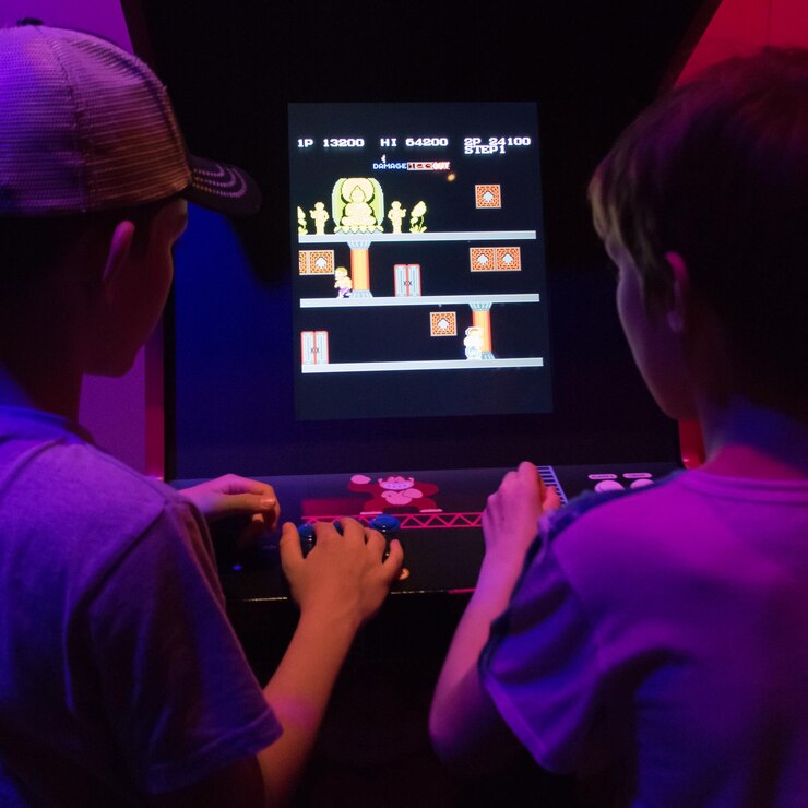 Foto dos niños jugando a un viejo juego de arcade