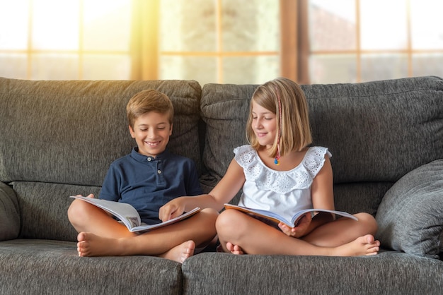 Dos niños leyendo y estudiando en el sofá de casa Regreso a la escuela Niños haciendo la tarea