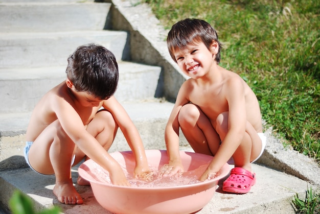 Dos niños lindos jugando con agua al aire libre