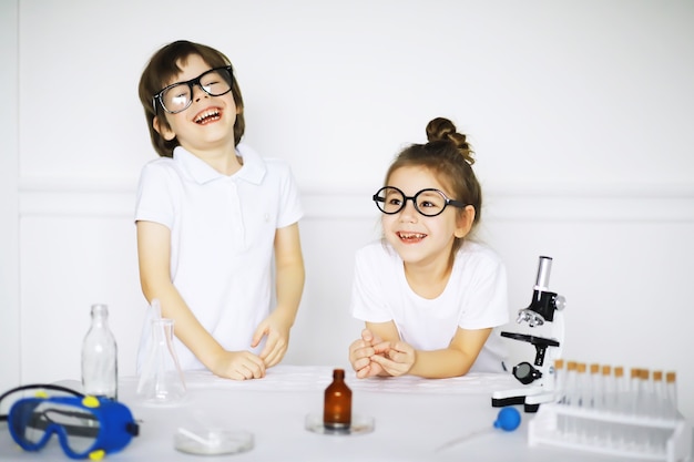 Dos niños lindos en la lección de química haciendo experimentos aislados sobre fondo blanco.