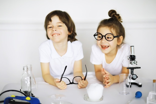 Dos niños lindos en la lección de química haciendo experimentos aislados sobre fondo blanco.