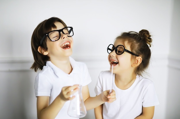 Dos niños lindos en la lección de química haciendo experimentos aislados sobre fondo blanco.