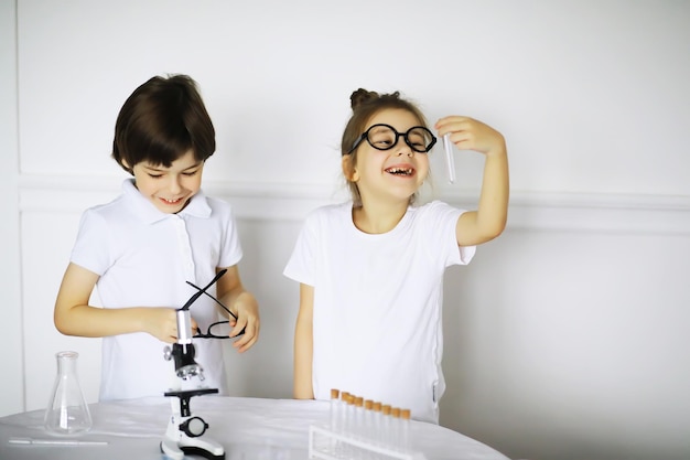 Dos niños lindos en la lección de química haciendo experimentos aislados sobre fondo blanco.