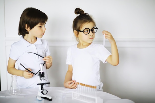 Dos niños lindos en la lección de química haciendo experimentos aislados sobre fondo blanco.