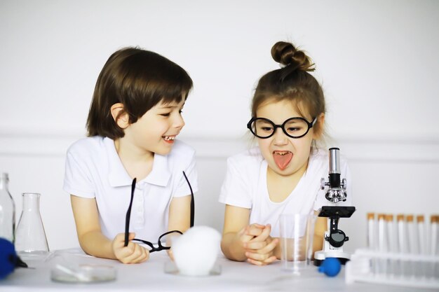 Dos niños lindos en la lección de química haciendo experimentos aislados sobre fondo blanco.