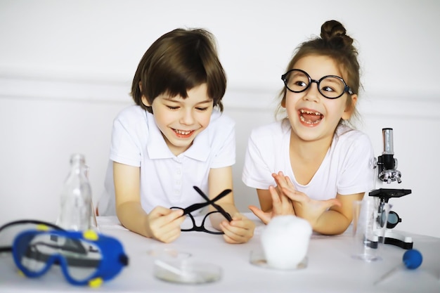 Dos niños lindos en la lección de química haciendo experimentos aislados sobre fondo blanco.