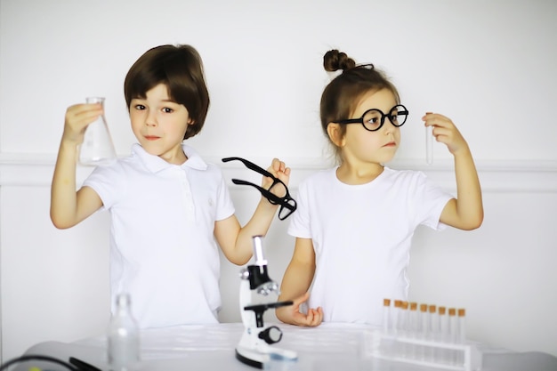 Dos niños lindos en la lección de química haciendo experimentos sobre fondo blanco.