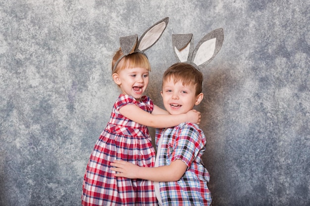 Dos niños, una niña y un niño con orejas de conejo de Pascua en la cabeza, se ríen y juegan Espacio de copia de Pascua familiar